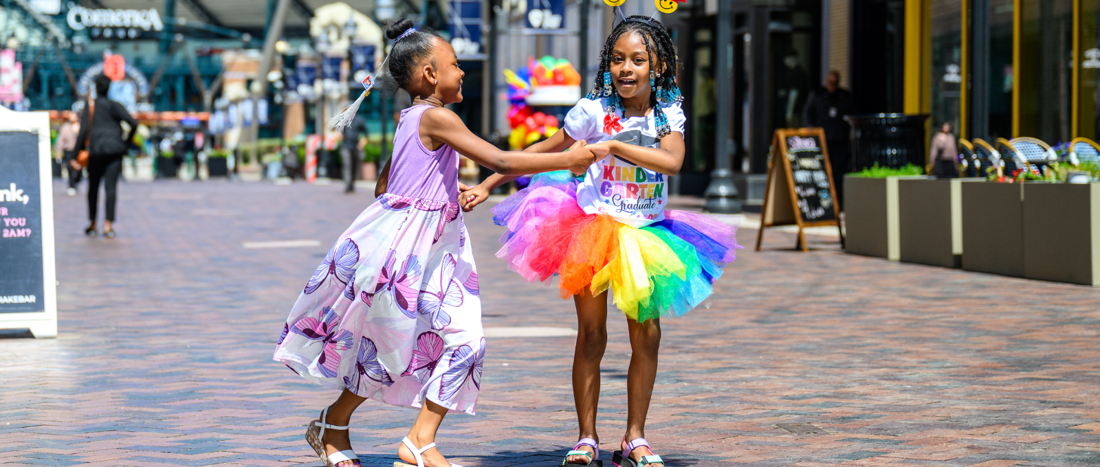 Two young girls dancing in rainbow attire on Columbia Street.